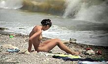 Une fille nue aux cheveux foncés se promène nue sur une plage