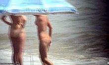 Wanita berambut gelap telanjang berjalan telanjang di pantai