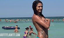素晴らしいボディを持つ巨乳のブルネットがビーチで日焼けを披露しています。